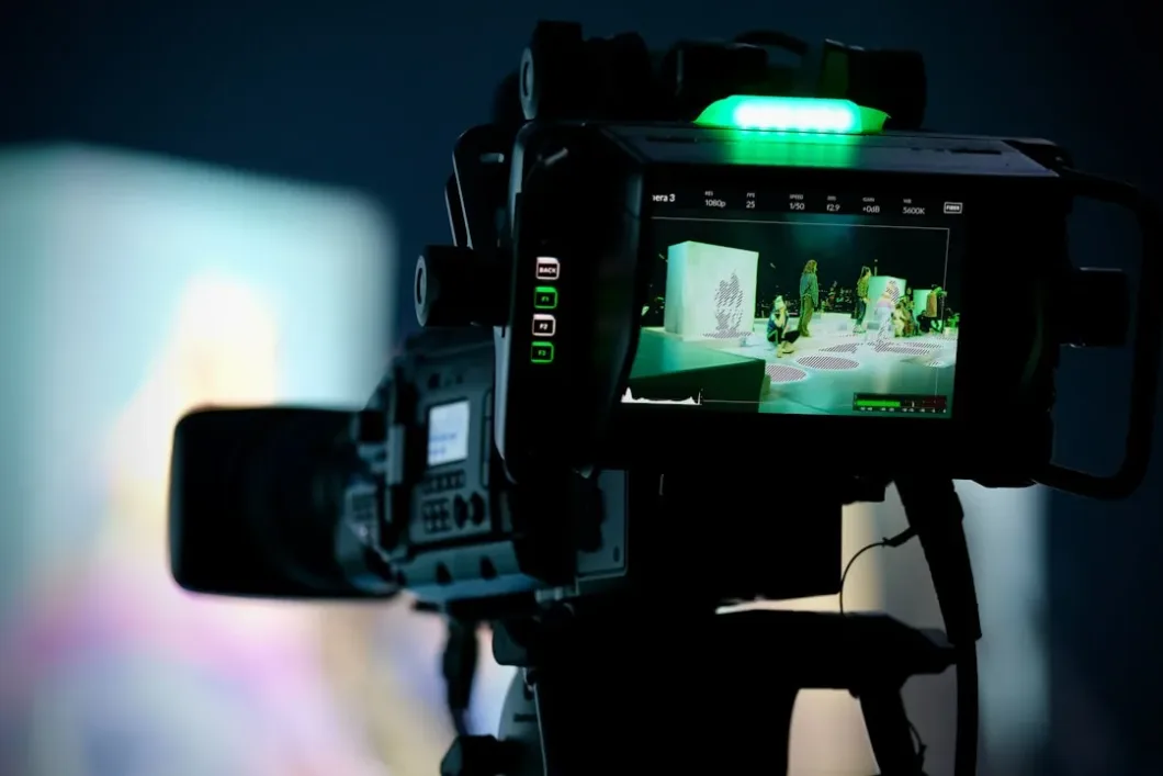 Professional video camera captures an event, green light illuminated.